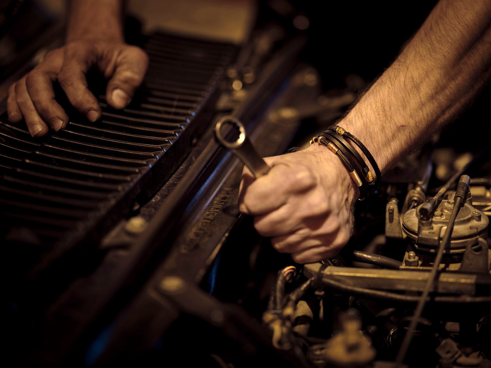 Mâinile unui mecanic lucrând la motor cu o cheie fixă